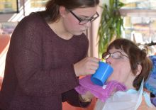 FSJlerin hilft einer Frau mit Behinderung beim Trinken
