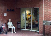 Vor dem Eingang eine alte Frau